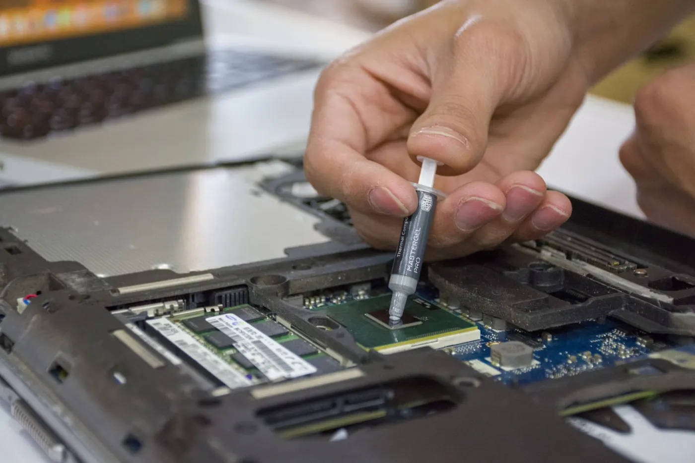 Aplicación de pasta térmica sobre el procesador de una laptop abierta